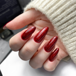 A close-up of a womans painted nails on her right hand. Nails are painted in a deep red with light black marbling and a glossy finish.