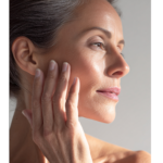 Closeup of midlife age woman whos holding her hand up to the right side of her face. The glowing condition of her skin indicates that she choses skincare products that work with her midlife skin.